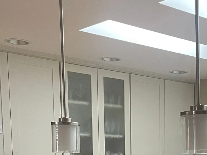 White kitchen cabinets, pendant light and skylight in a kitchen Rosy cleaned